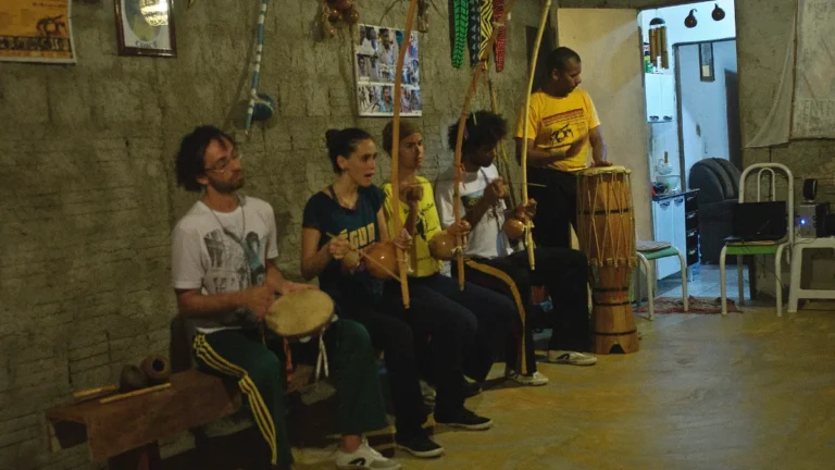 Músicos de capoeira angola tocando berimbau, pandeiro e atabaque na roda