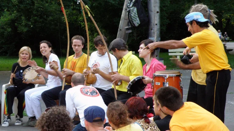 Capoeiristas tocando berimbaus e cantando em uma roda de capoeira ao ar livre